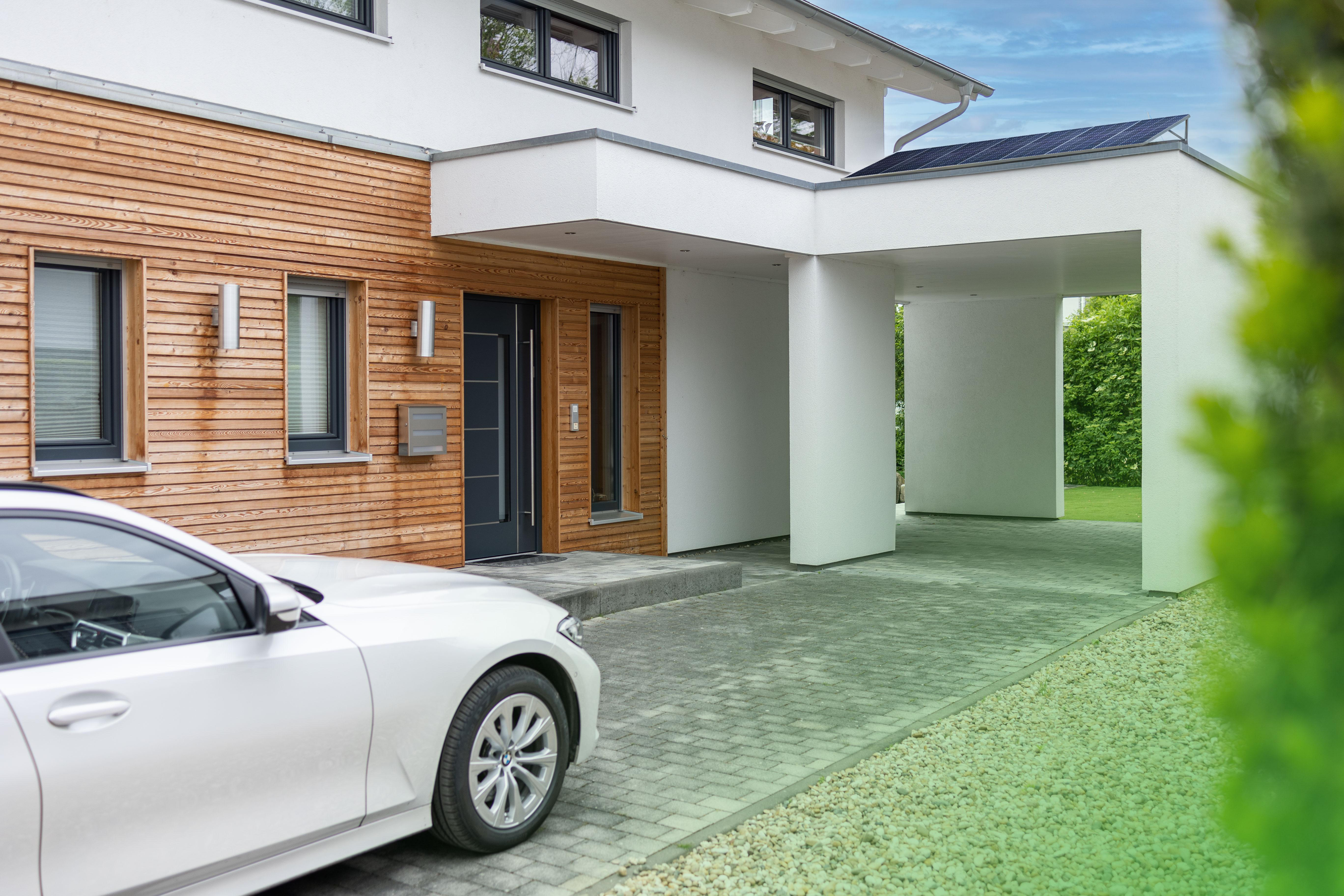 Ein modernes Haus mit einem Auto vor einem Carport geparkt.