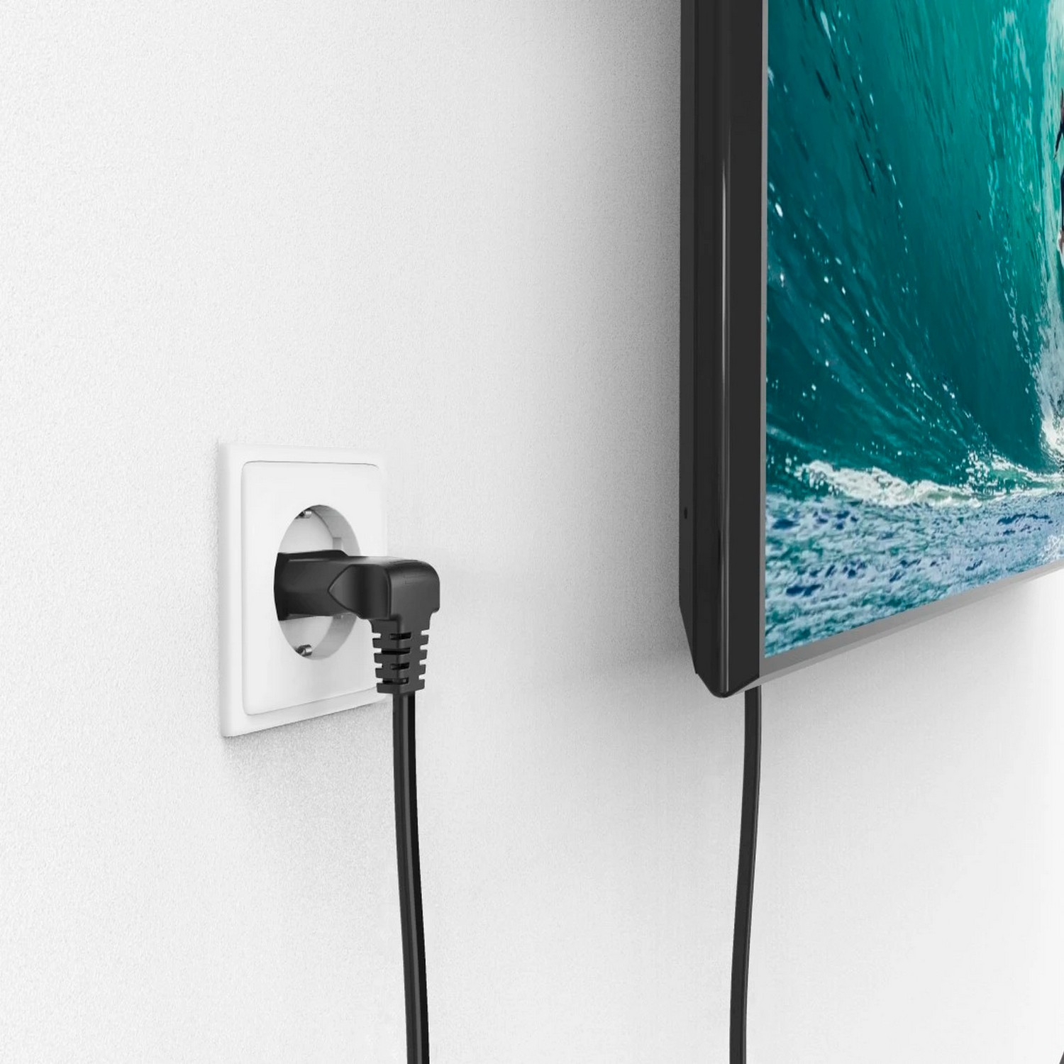 A black power cord plugged into a white wall outlet, with a TV in the background.