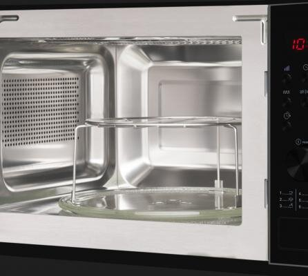 Wnętrze kuchenki mikrofalowej. Jest szklany talerz i metalowa konstrukcja.