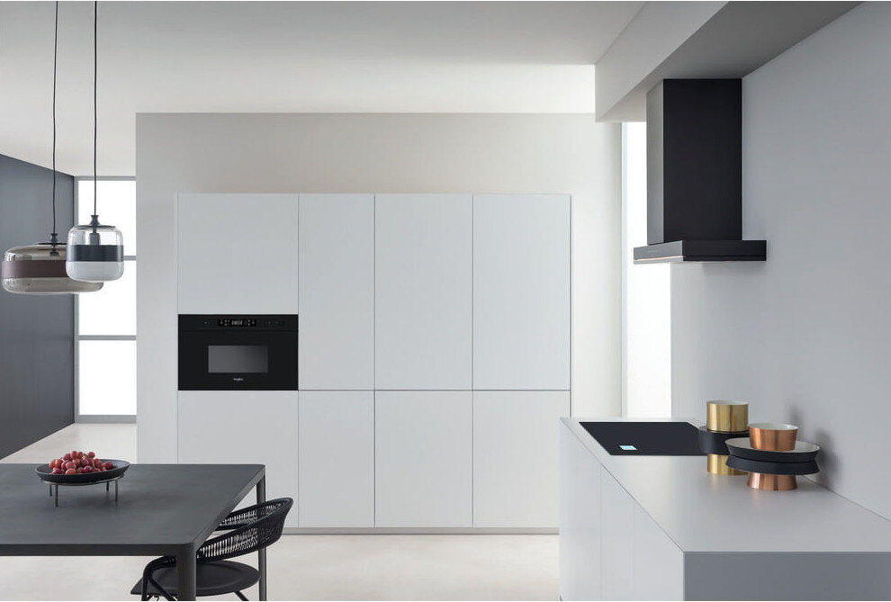 Nowoczesna biała kuchnia ze sprzętem oraz czarnym stołem i krzesłami.