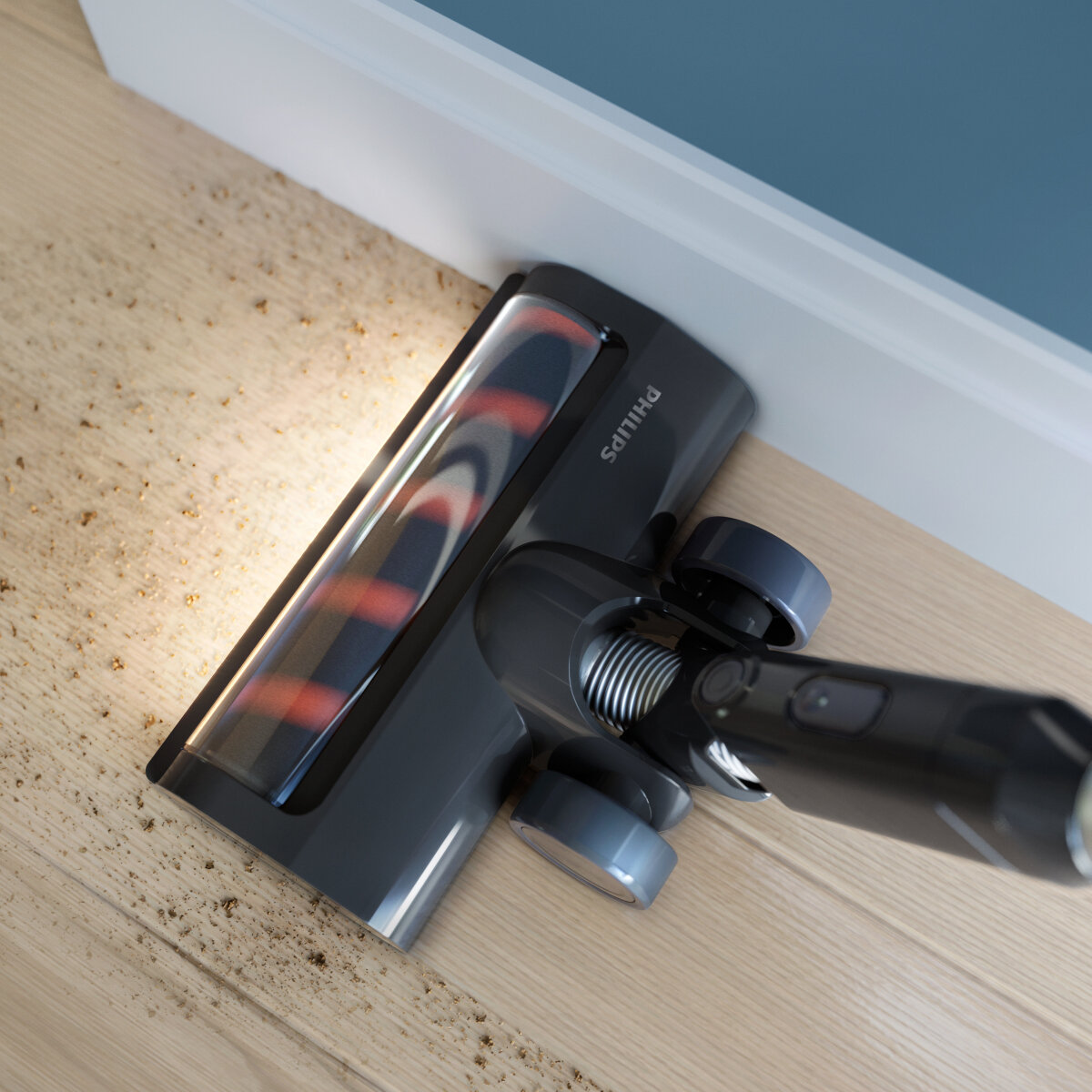 Głowica odkurzacza na drewnianej podłodze, czyszczenie w pobliżu listwy przypodłogowej. Jasne i ciemne drewno.