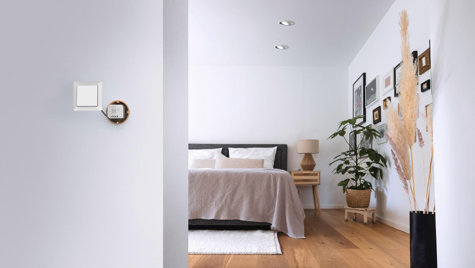 Ein Schlafzimmer mit Bett, Nachttisch und Galeriewand auf der rechten Seite.
