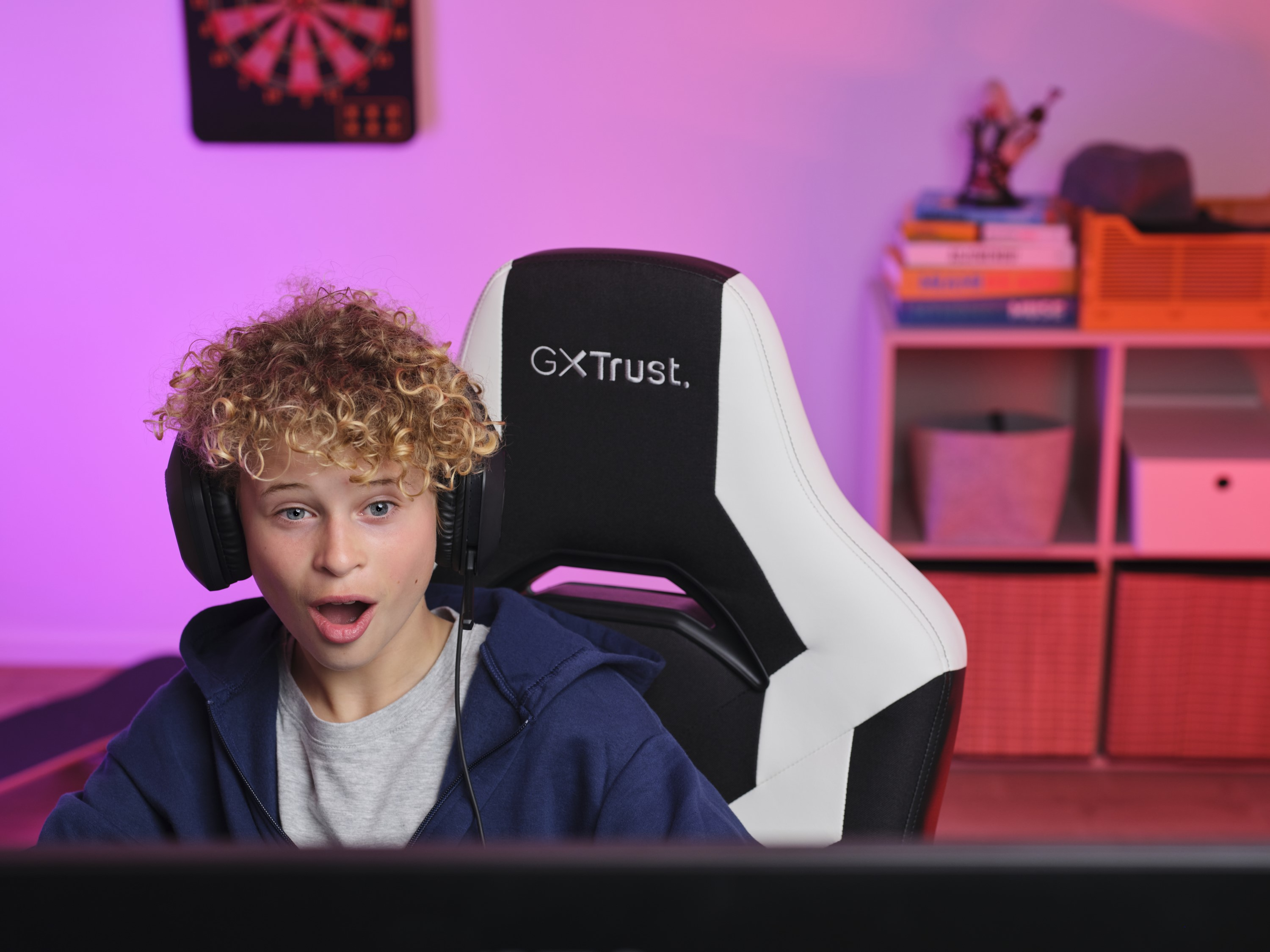 Un jeune garçon avec un casque, jouant à des jeux vidéo, l'air excité.
