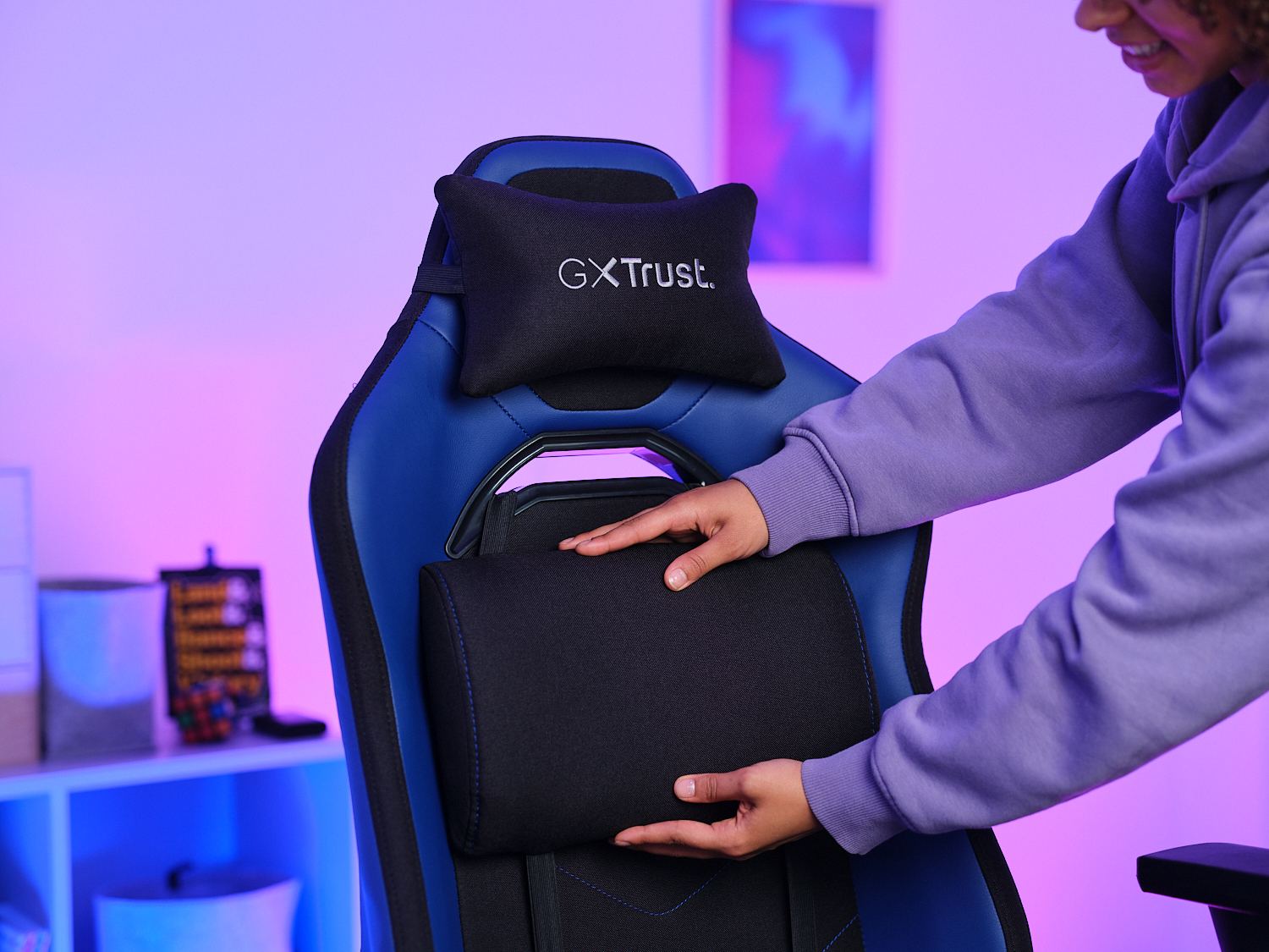 Personne ajustant un appui-tête noir sur une chaise de jeu bleue et noire.
