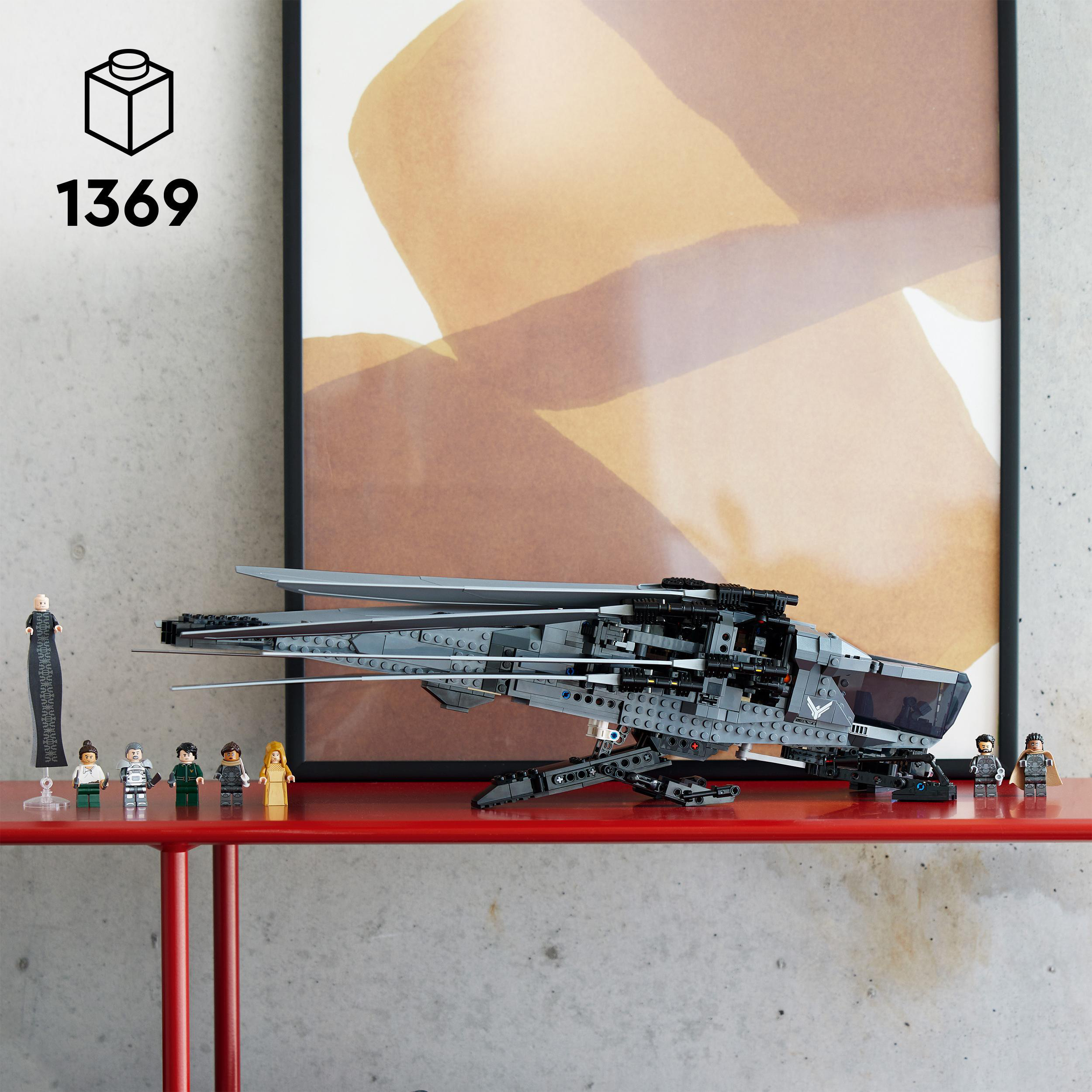Lego-Schiffsmodell auf rotem Tisch, mit Minifiguren und einem schwarz-weißen Bildrahmen.