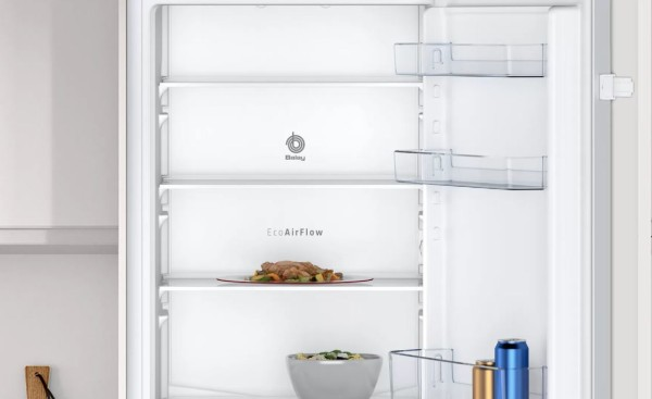Interior de refrigerador con estantes y alimentos. Tonos blancos y plateados.