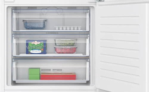 Interior de un refrigerador con cajones de congelador abiertos. Se ven alimentos, incluyendo guisantes y hielo.