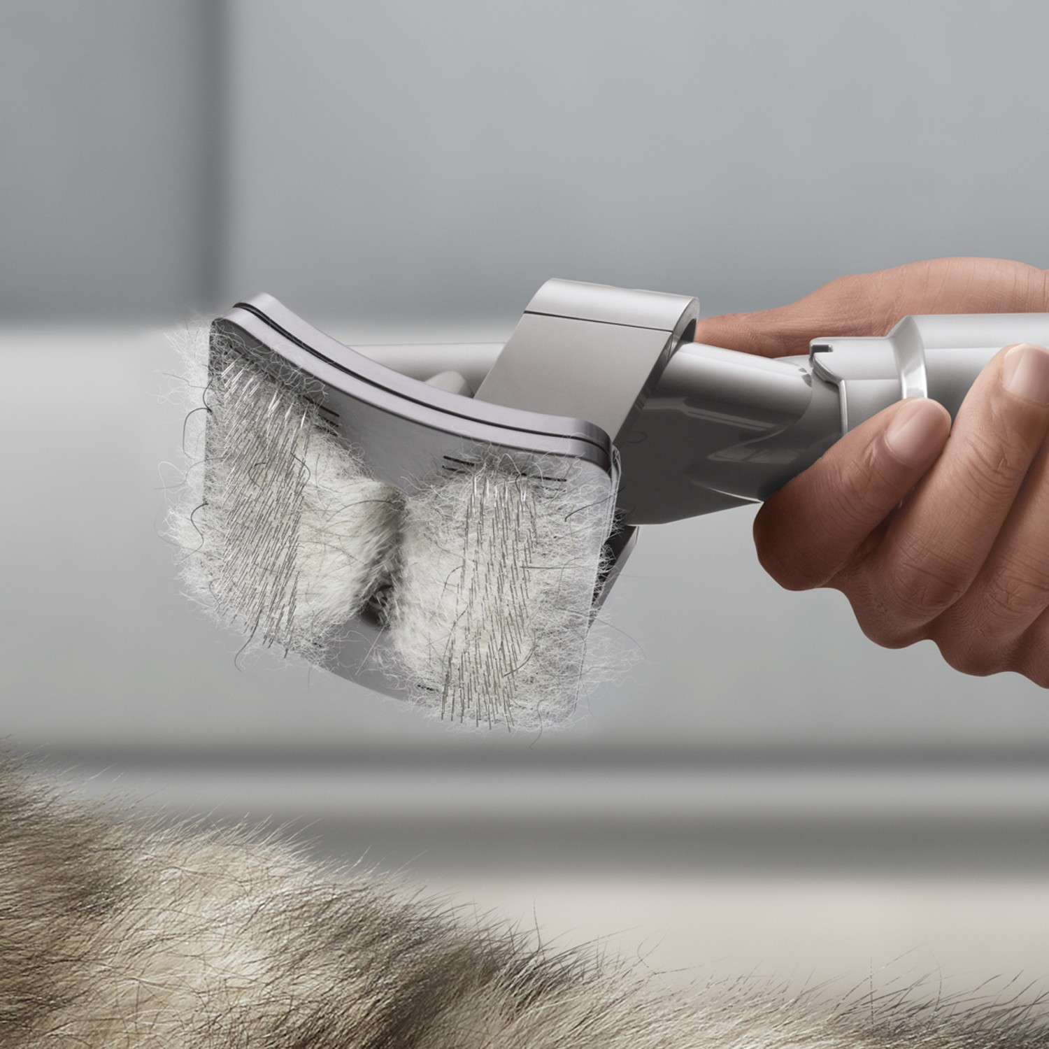 Personne utilisant une brosse d'aspirateur sur un canapé, enlevant les poils de chat. L'accessoire a des brosses.