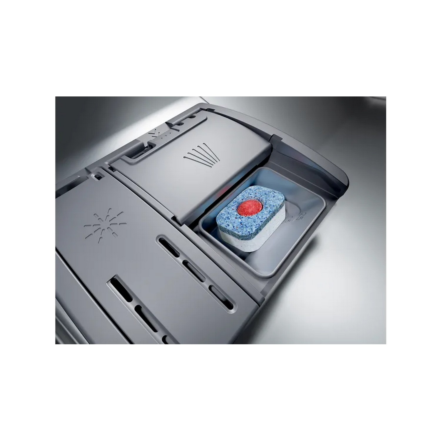 Dishwasher compartment with a detergent tablet. Tablet is blue with red center. Gray compartment.