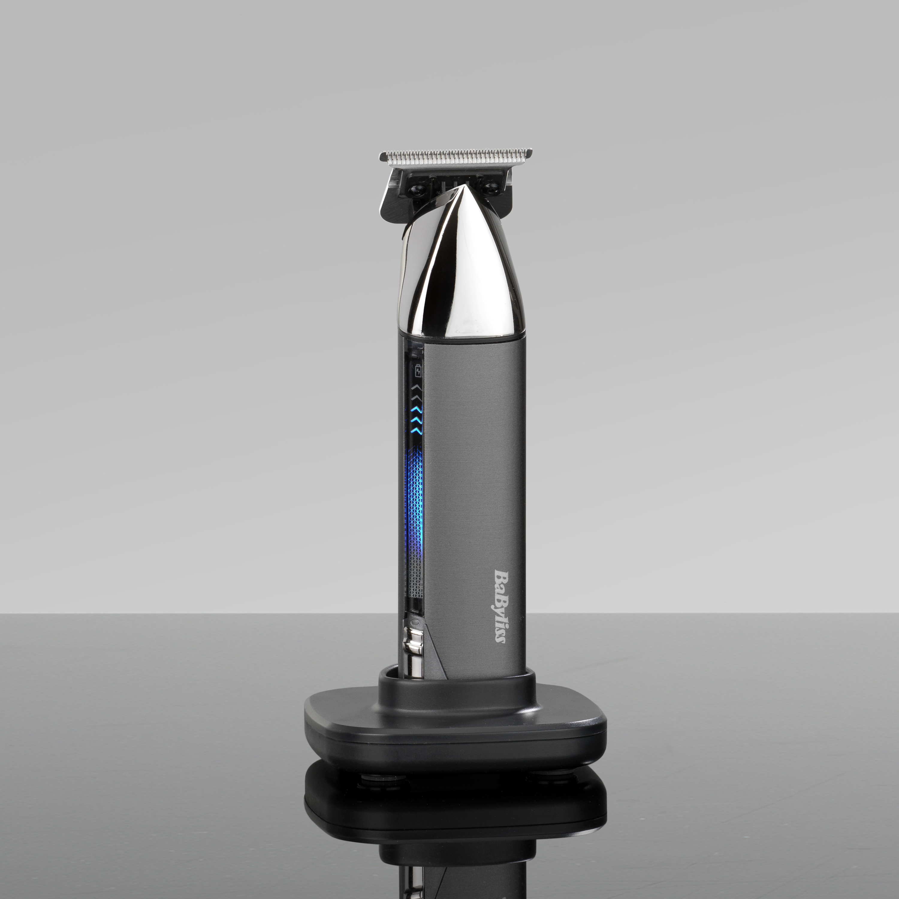 Ein grauer Babyliss Haartrimmer in seiner Ladestation auf glänzender Oberfläche.