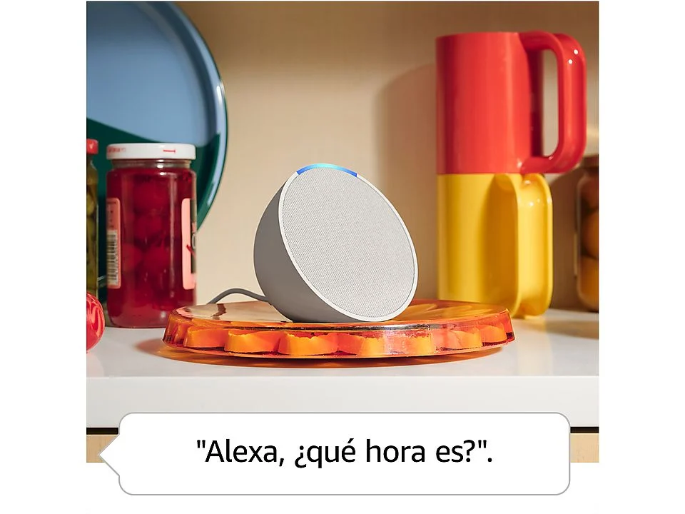Altavoz inteligente gris en bandeja naranja. Tazas rojas y amarillas detrás.