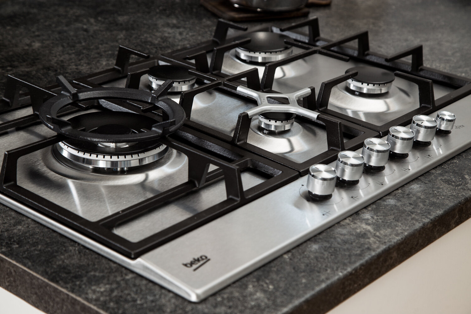 Płyta gazowa Beko ze stali nierdzewnej z czterema palnikami i pokrętłami, na ciemnej powierzchni.