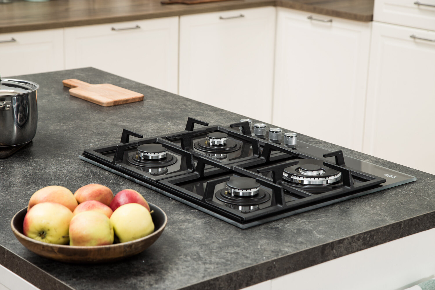 Blat kuchenny z płytą indukcyjną i miską jabłek z deską do krojenia.