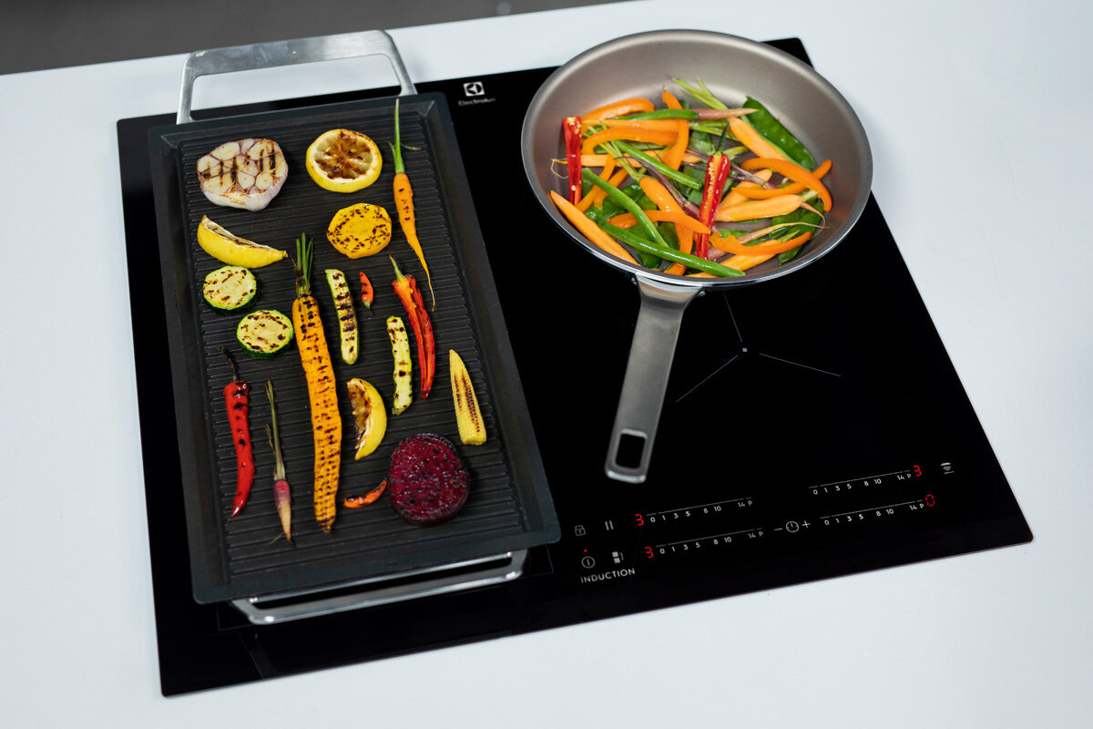 Warzywa grillowane na czarnym grillu i smażone na patelni na czarnej płycie indukcyjnej.