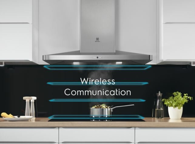 Scena kuchenna z okapem, płytą grzejną i garnkiem. Niebieskie linie przedstawiają komunikację bezprzewodową.