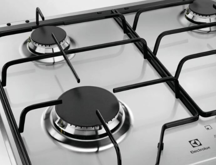 Zbliżenie kuchenki gazowej ze stali nierdzewnej z czarnymi rusztami.