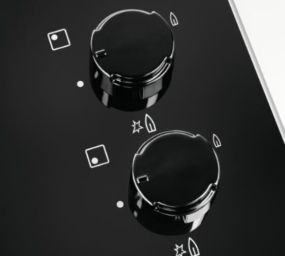 Zbliżenie czarnych pokręteł piekarnika z białymi symbolami palników i funkcji.