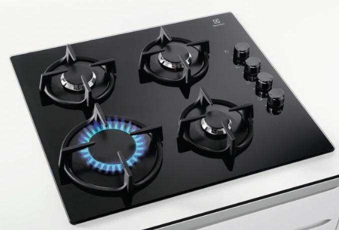 Czarny palnik z czterema palnikami i pokrętłami. Jeden palnik ma niebieski płomień.