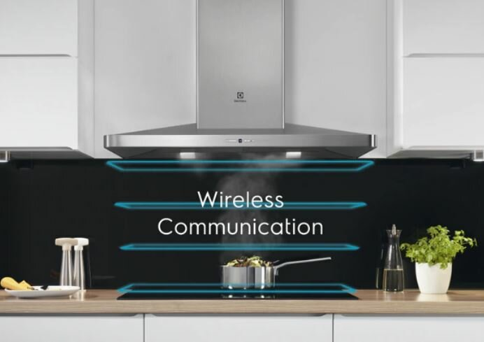 Scena kuchenna z okapem i garnkiem na płycie indukcyjnej.