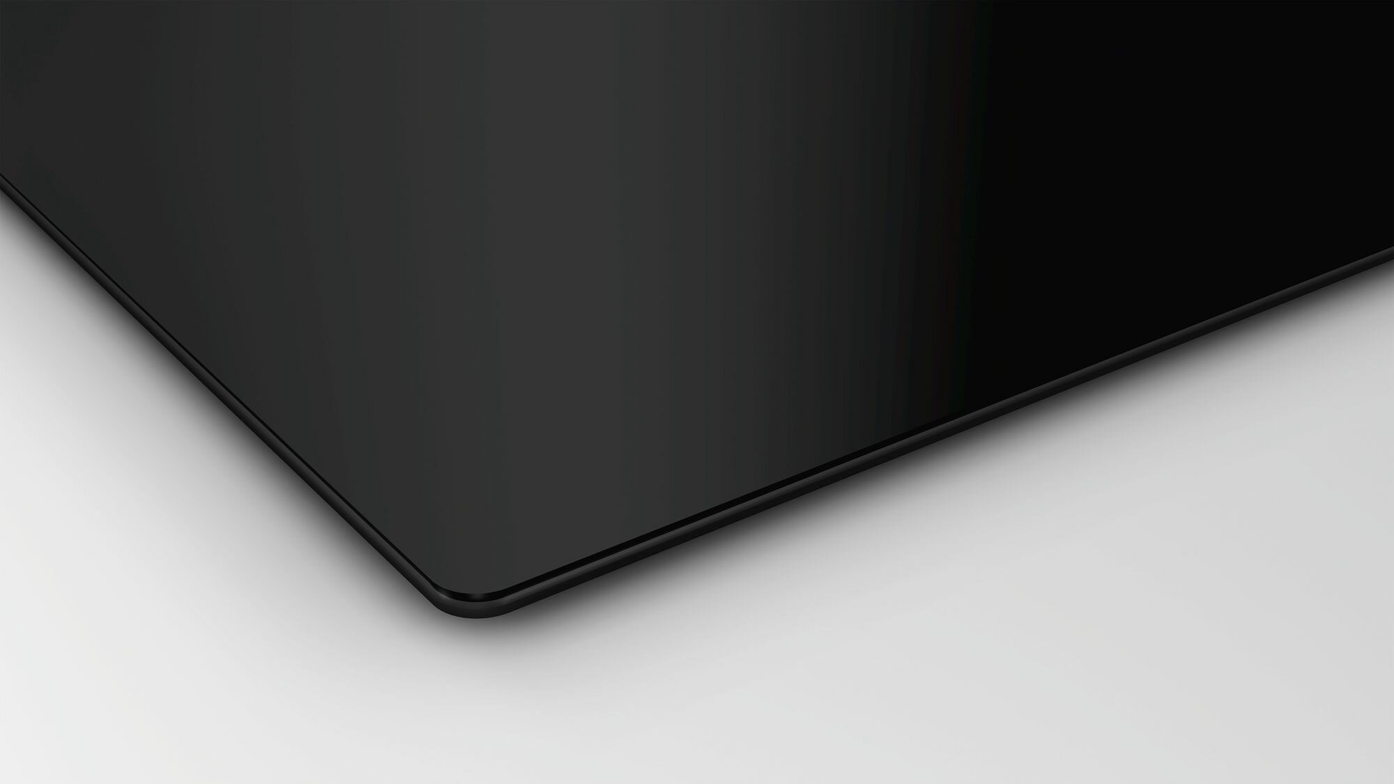 Błyszcząca czarna powierzchnia, prawdopodobnie płyta grzewcza lub podobne urządzenie, na białym tle.