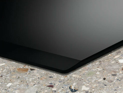 Zbliżenie czarnej powierzchni płyty grzejnej z nakrapianym blatem.