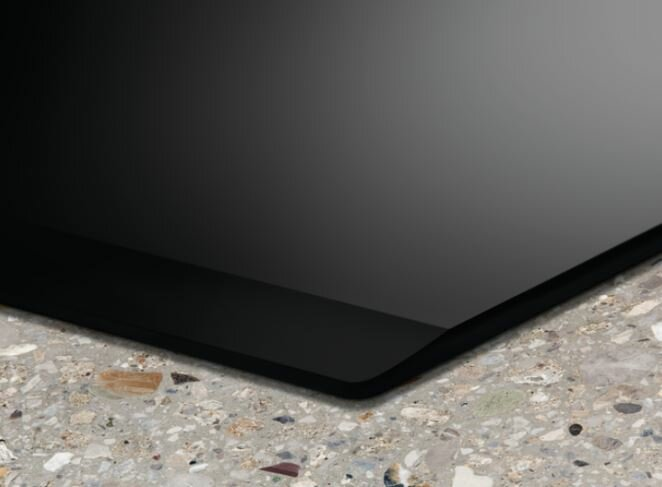 Czarny blat kuchenny z gładką, błyszczącą powierzchnią na nakrapianym blacie.