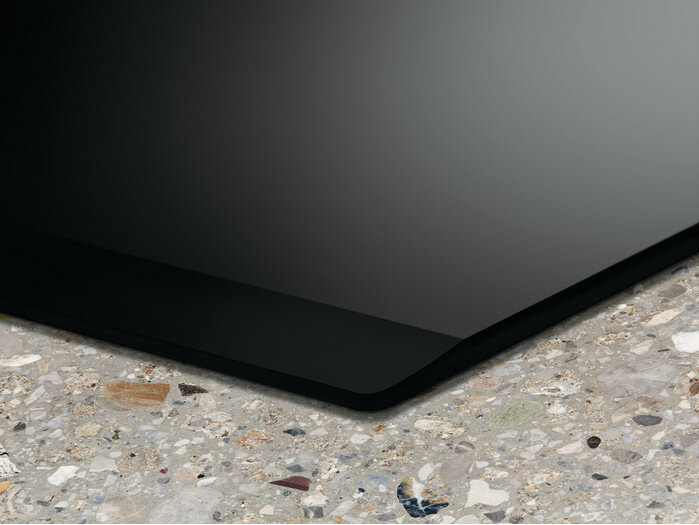 Zbliżenie czarnej powierzchni płyty grzejnej na nakrapianym granitowym blacie.