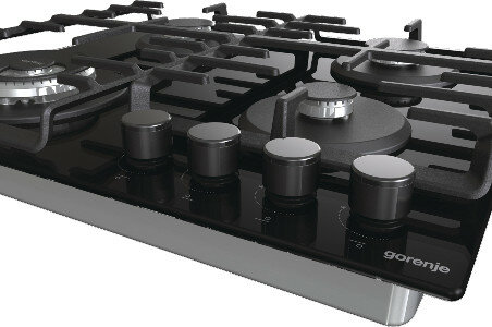 Zbliżenie czarnej kuchenki gazowej z czterema pokrętłami. Kuchenka ma metalowe ruszty i palniki z logo Gorenje.