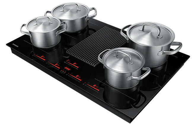 Czarna płyta indukcyjna ze stalowymi garnkami na wierzchu.