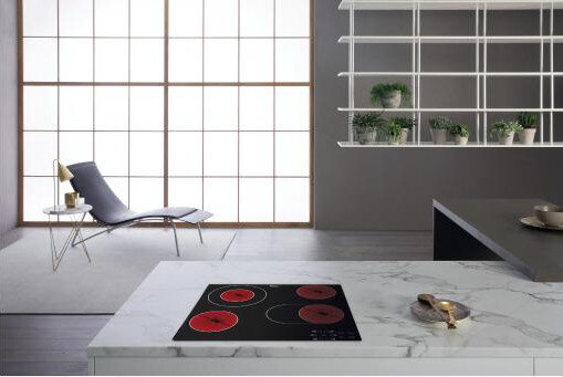 Nowoczesna kuchnia z płytą grzewczą z czerwonymi okręgami, krzesłem i białymi półkami.