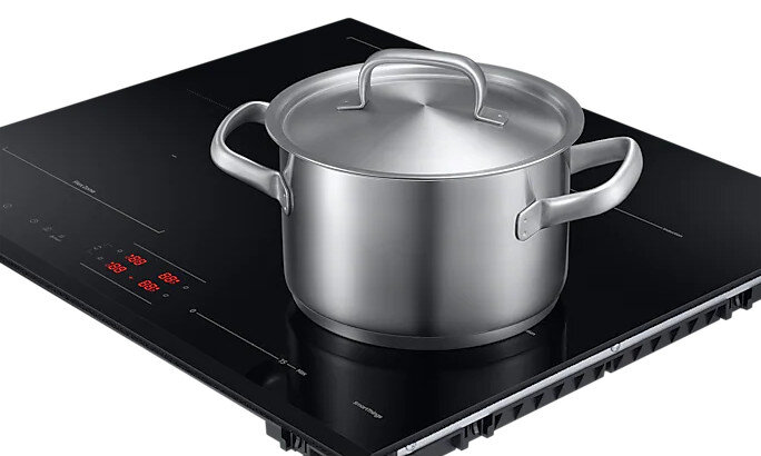 Garnek ze stali nierdzewnej na czarnej płycie indukcyjnej.