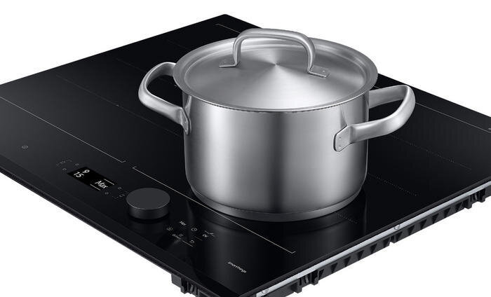 Srebrny garnek na czarnej płycie indukcyjnej. Widoczny panel sterowania.