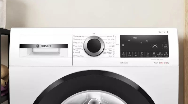 Bedieningspaneel van wasmachine met centrale draaiknop, digitaal display en diverse pictogrammen.
