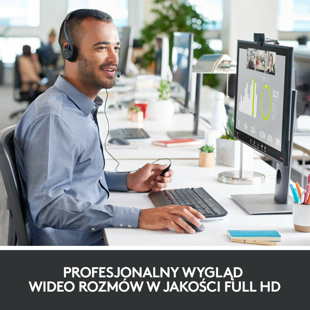 Mężczyzna w zestawie słuchawkowym używający komputera z monitorem wyświetlającym rozmowę wideo.