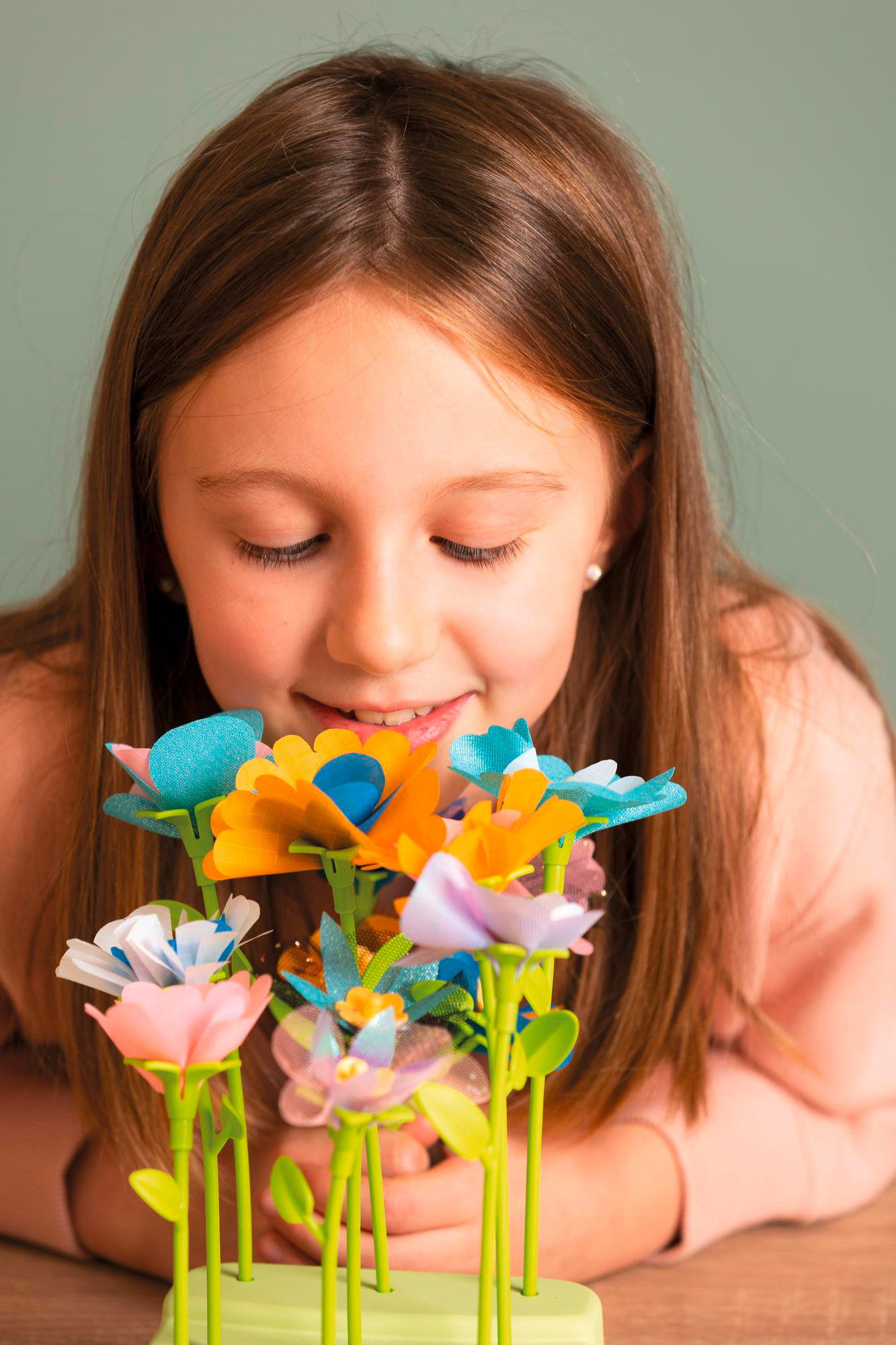Ein Mädchen betrachtet bunte Papierblumen. Die Blumen sind in verschiedenen Farben.