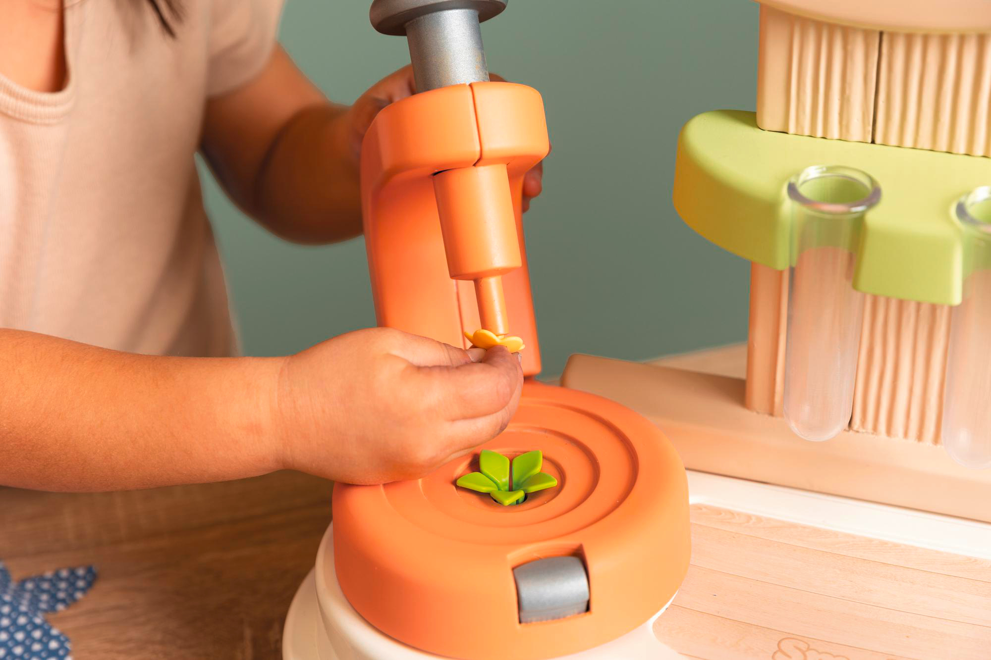 Kinderhand benutzt ein orangefarbenes Wissenschaftsspielzeug mit Blüte.