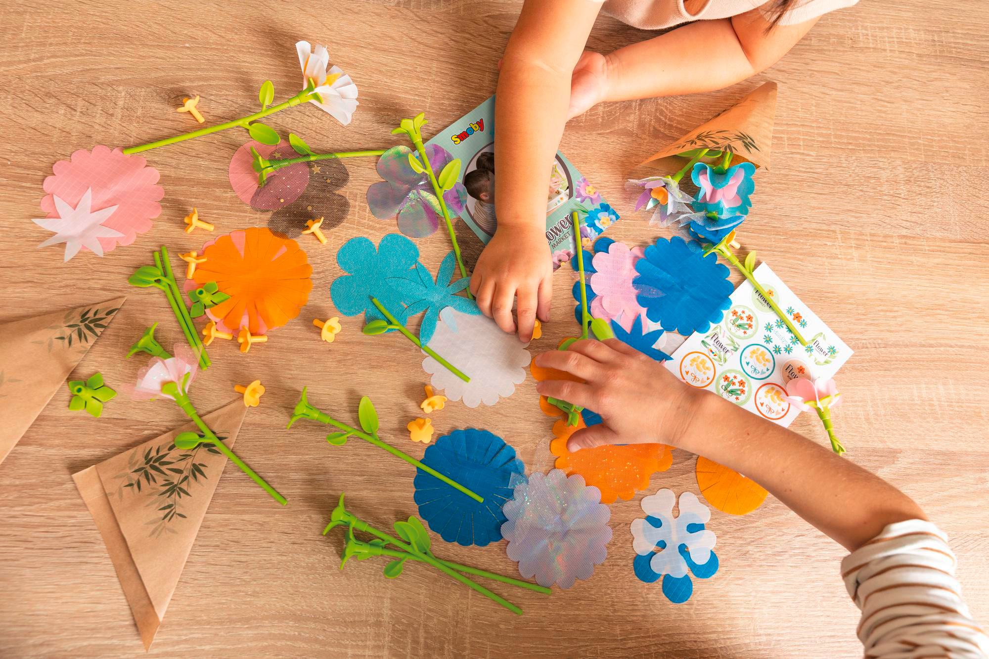Hände eines Kindes und eines Erwachsenen, die mit Papierblumen spielen.