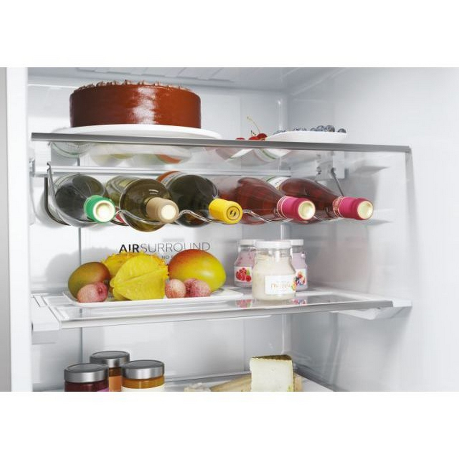 Koelkastinterieur met planken met voedsel zoals taart, fruit en flessen.
