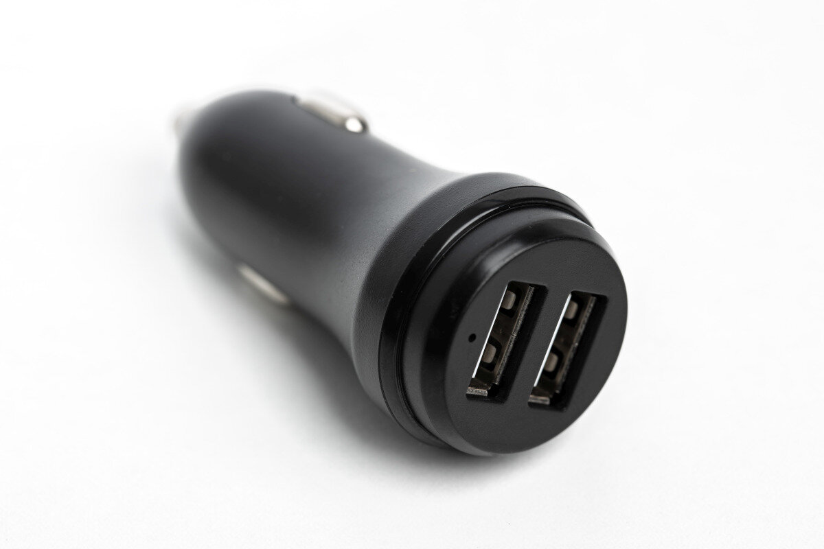 Czarna ładowarka samochodowa z dwoma portami USB na białym tle.