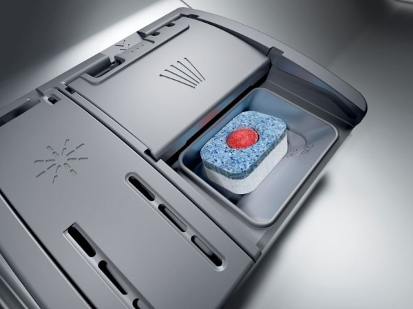 Vaatwasmiddel compartiment met een tablet erin. Het compartiment is grijs, de tablet blauw, rood en wit.