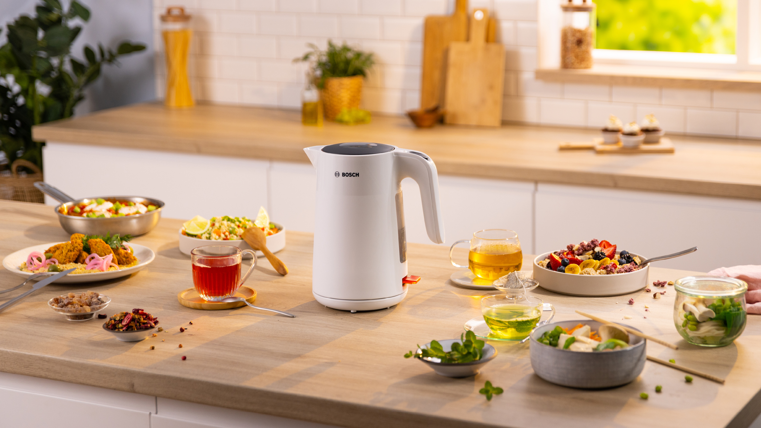 Eine Küchenszene mit einem weißen Wasserkocher und Gerichten mit Essen.