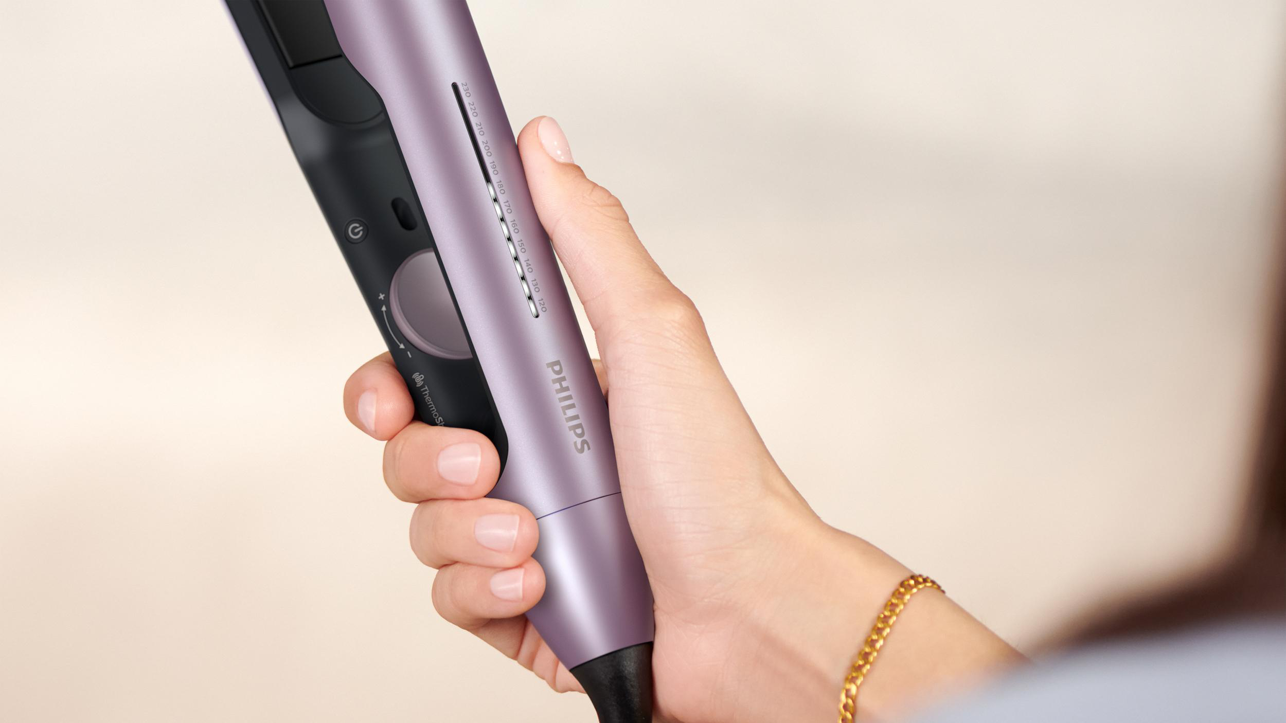 Eine Hand hält einen lila-schwarzen Philips Haarglätter mit Knöpfen und Einstellungen.
