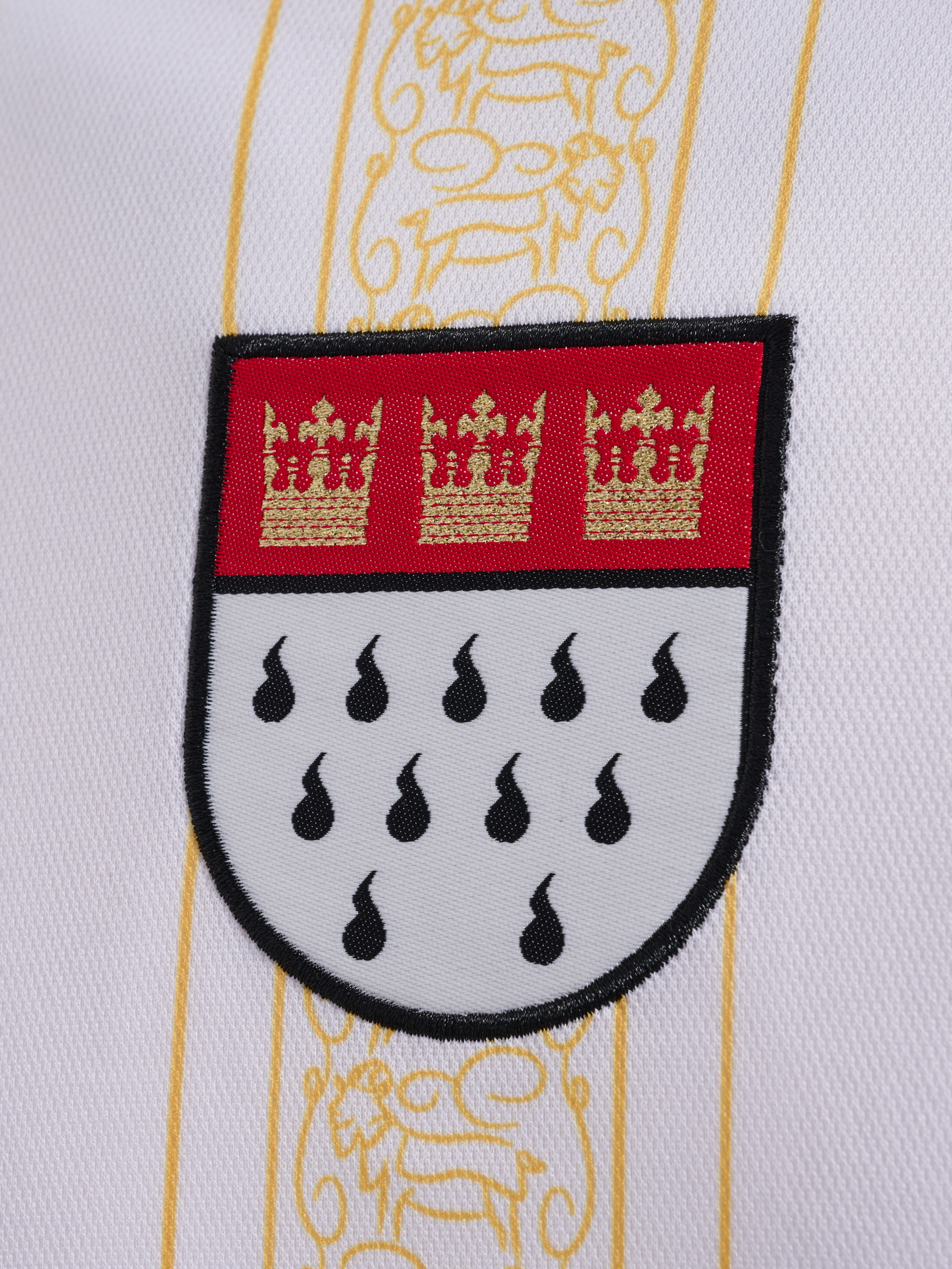Nahaufnahme eines weißen Fußballtrikots mit einem Team-Abzeichen mit drei goldenen Kronen.