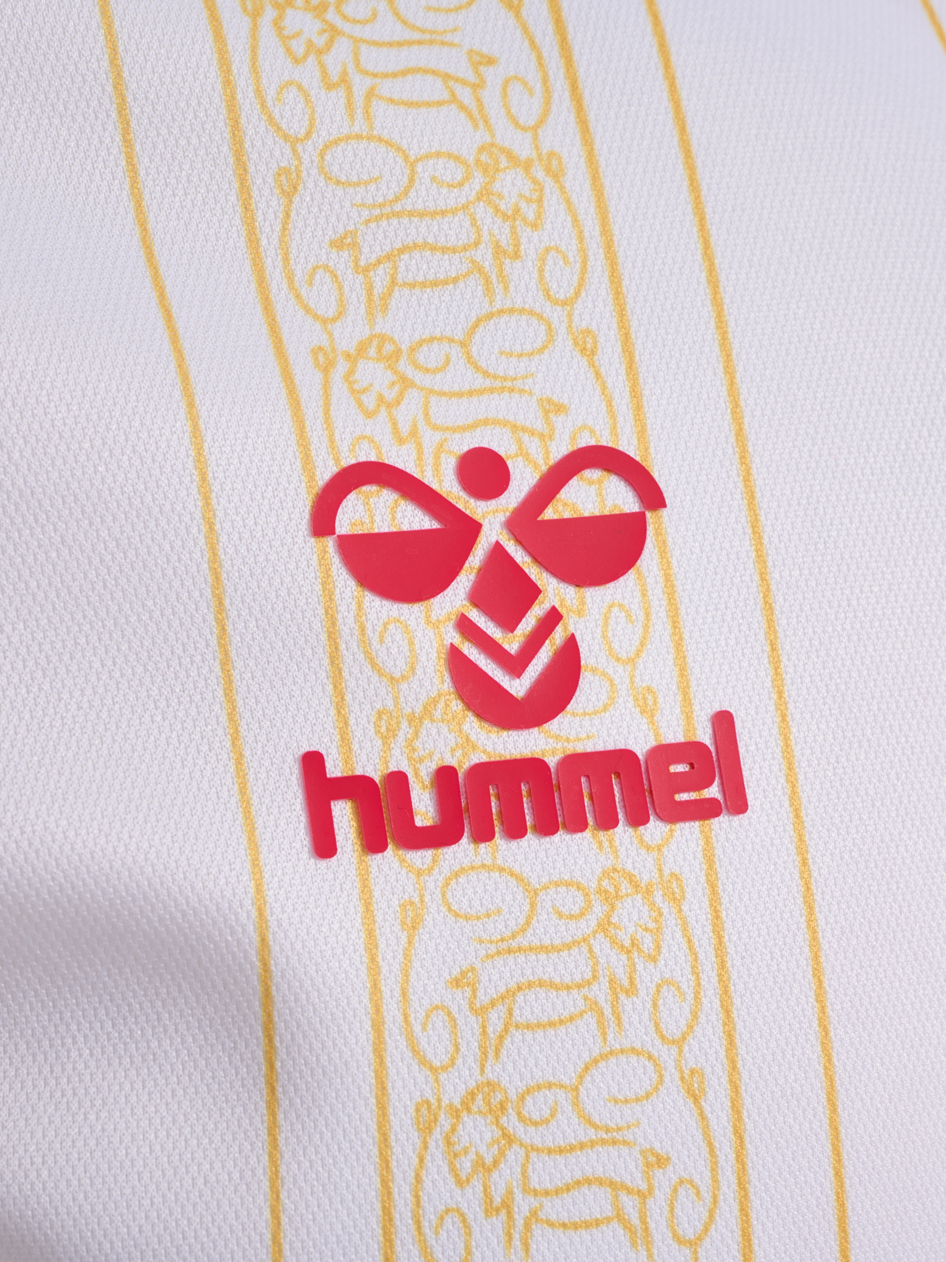 Nahaufnahme eines weißen Hemdes mit gelben Streifen und einem roten 'hummel'-Logo.