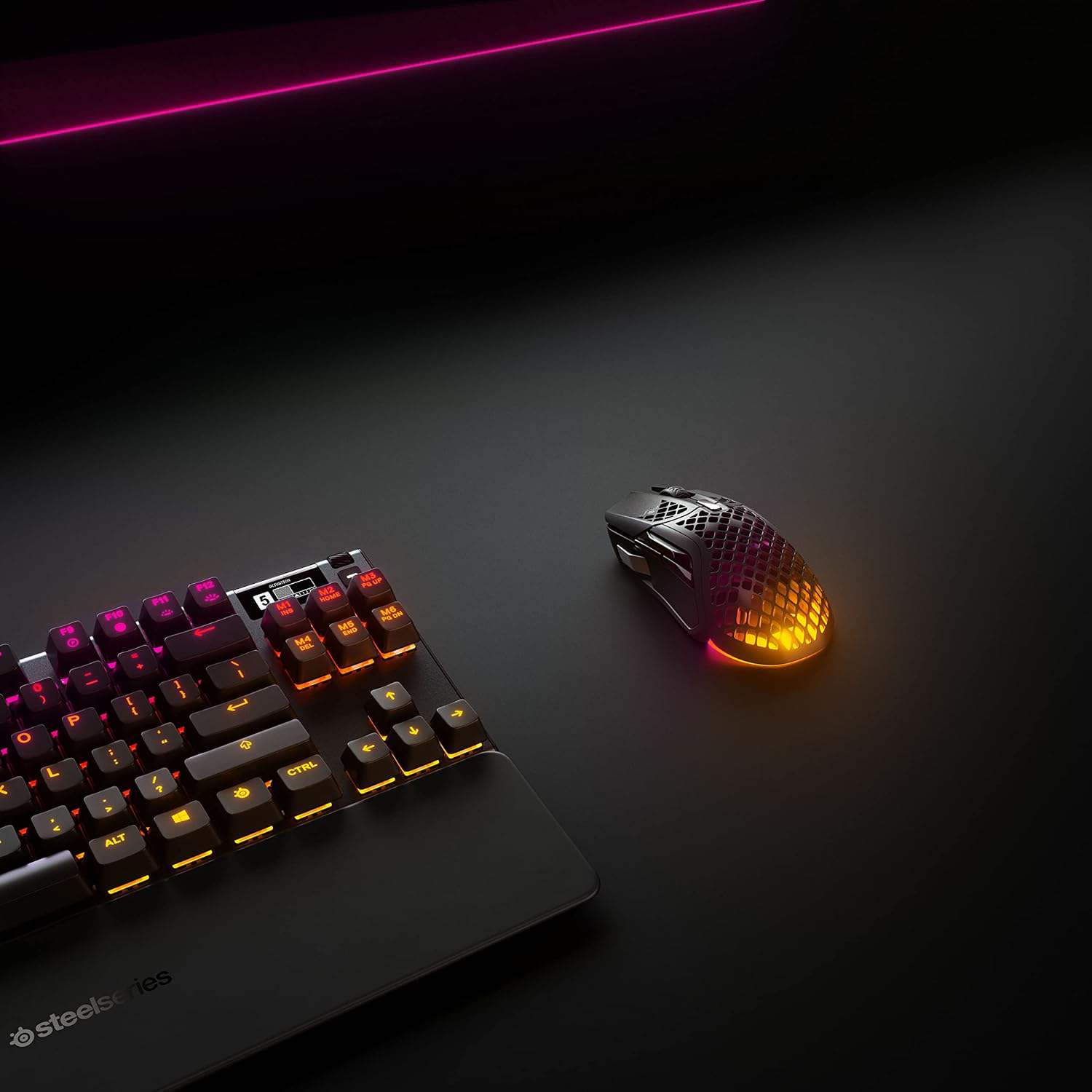Un setup di gioco con tastiera e mouse, illuminato con luci arancioni e rosa.