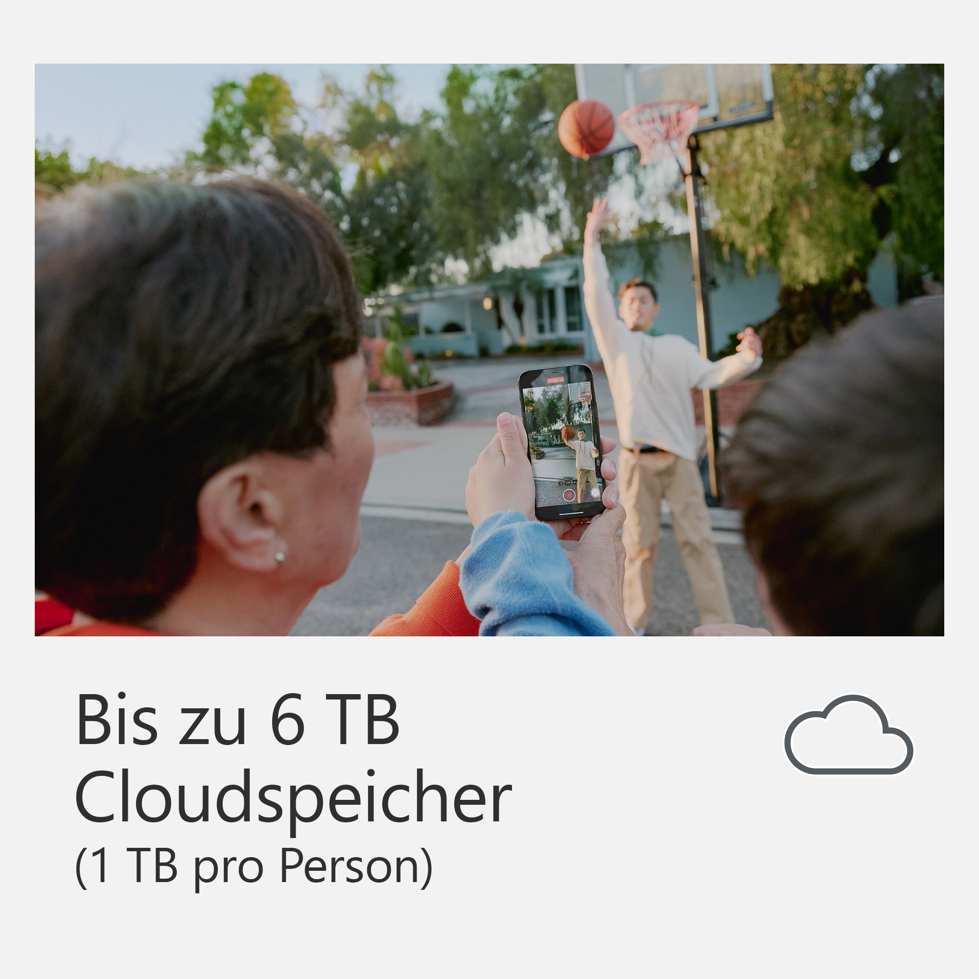 Due persone tengono un telefono che registra un uomo che gioca a basket.