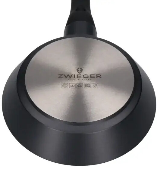 Spód czarnej patelni ze srebrnym logo Zwieger i symbolami.