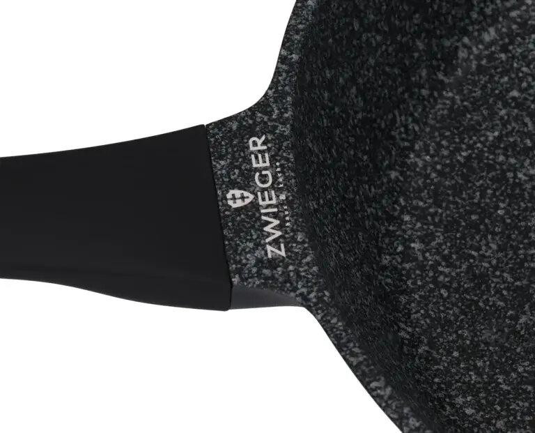 Zbliżenie na czarną patelnię z ciemnym uchwytem i widocznym logo 'ZWIEGER'.