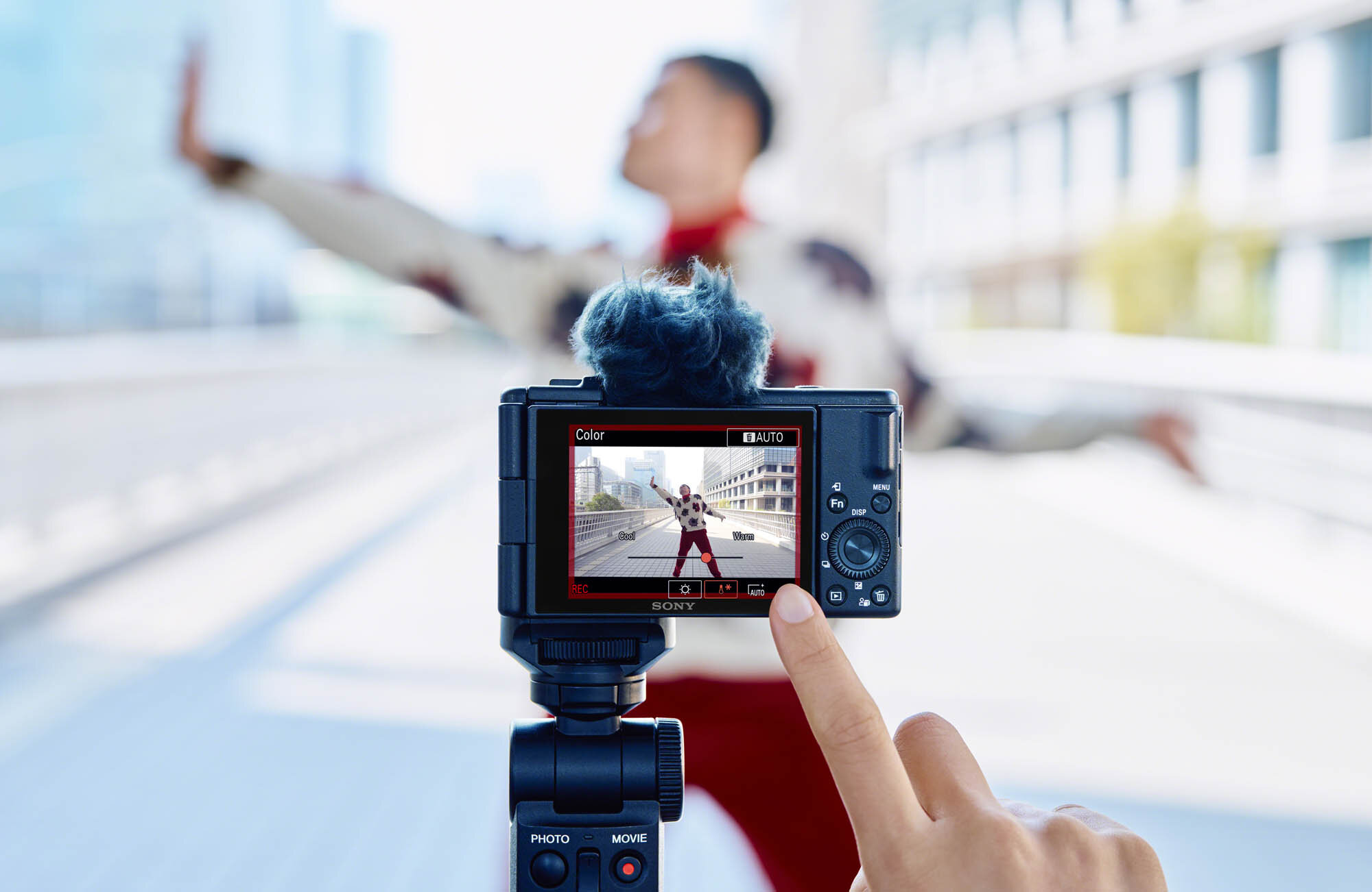 Osoba filmująca inną osobę kamerą. Ekran kamery pokazuje mężczyznę w czerwonej koszuli.