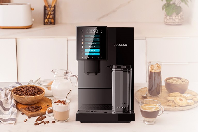 Cafetera Cecotec negra con pantalla táctil, varias tazas de café y cuencos de granos sobre superficie blanca.